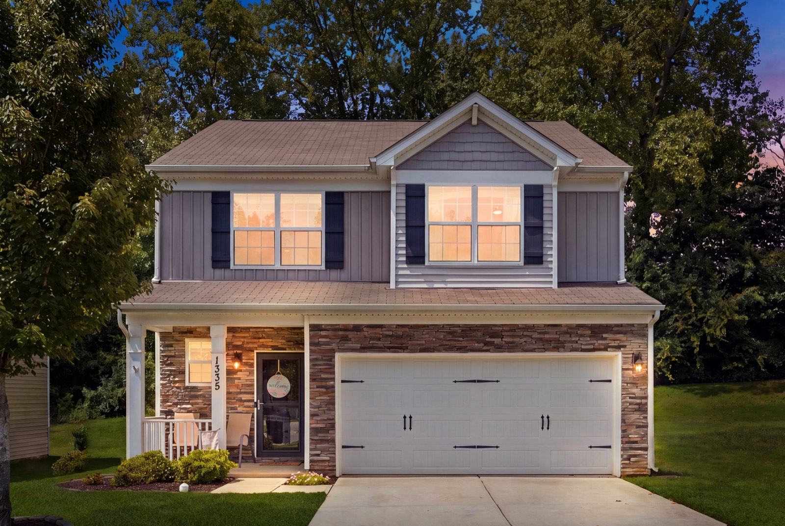 1335 Soothing Court NW at dusk — stone-front two-story with a covered porch and two-car garage